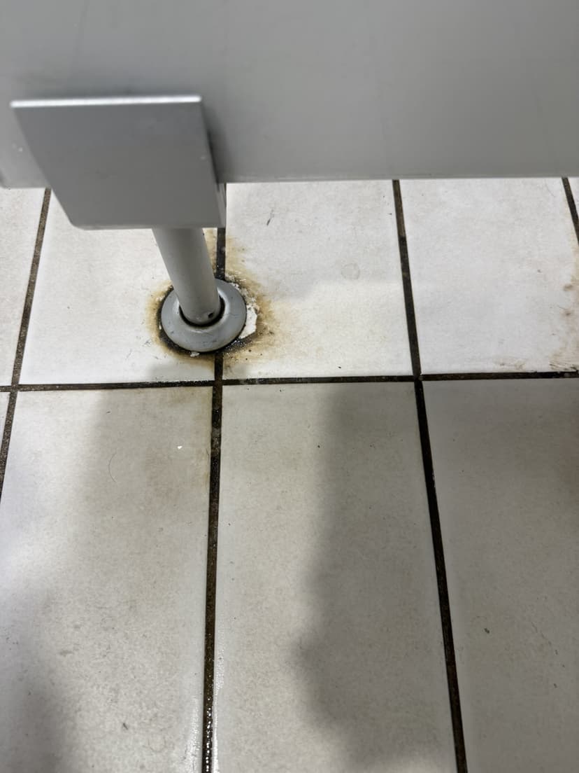 Before — rust and grime ringed around the cubicle fittings.